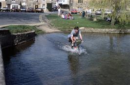 John Stuart tackles the ford at Sherbourne Street, Bourton-on-the-Water, with style