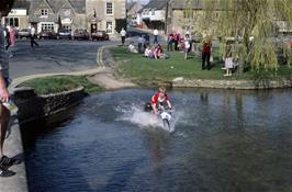 Martin Burrows takes a shot at the ford at Bourton-in-the-Water, now with several spectators